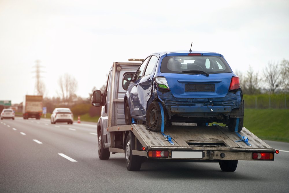 blue car trailer is being towed by tow truck 1 1